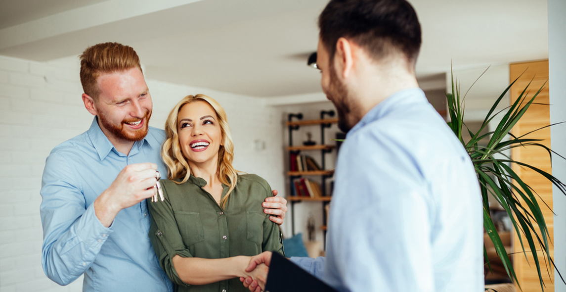 A Couple giggling and handshaking with house agent